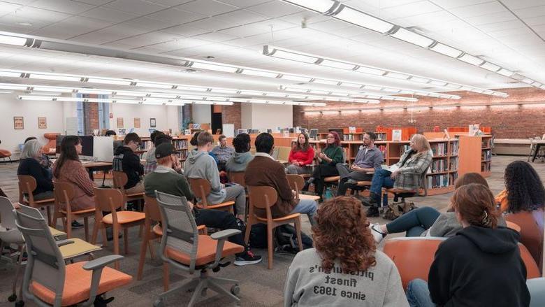 Students and guests listen to faculty speaking panel in library